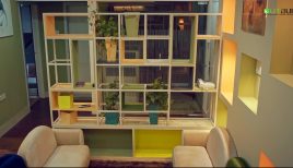 A welcoming office lobby interior by Outbuild BD, showing the functional geometric shelf as a room partition and a comfortable lounge seating area.